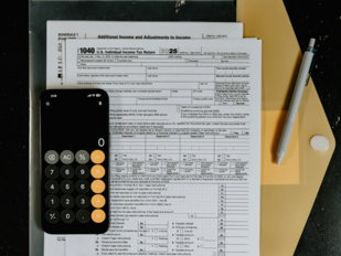Tax forms with calculator and pen on desk